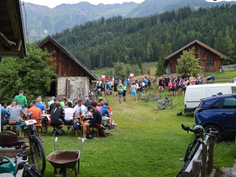 Teilnehmer der Rabantalm Trophy 2025 versammeln sich mit Fahrrädern vor Almhütten, im Hintergrund Berge und Wald
