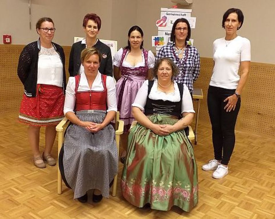 Eine Gruppe von sieben Frauen posiert gemeinsam in einem Innenraum