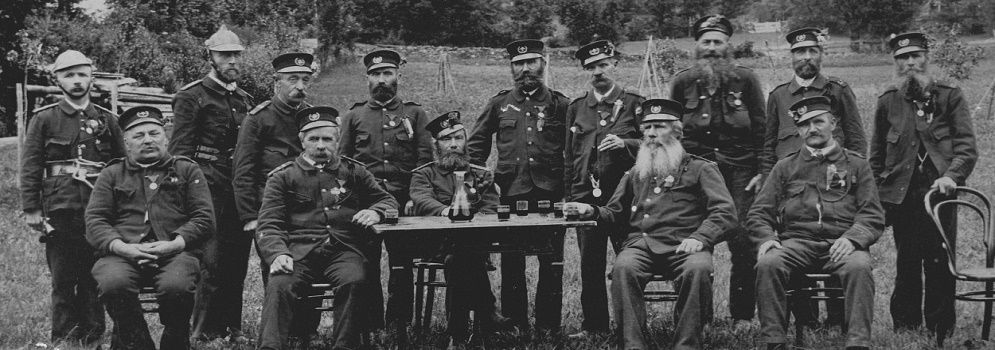 Ein historisches Schwarz-Weiß-Gruppenporträt von Männern in Uniform, einige mit Orden, die an einem Tisch sitzen.