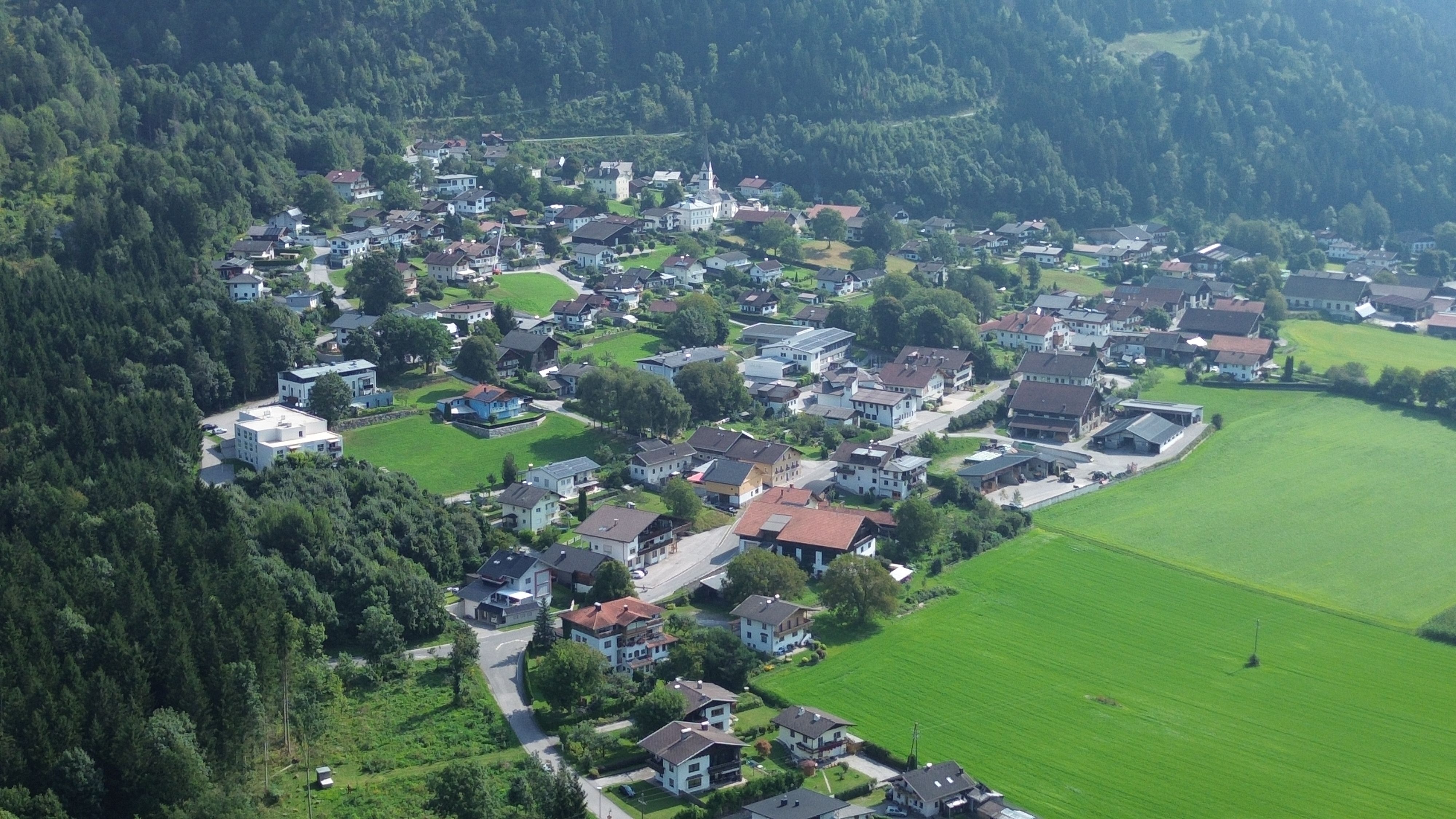 Drohnenaufnahme vom Ortskern der Gemeinde Nikolsdorf auf der zahlreiche Häuser, Straßen sowie einige Felder zu sehen sind.