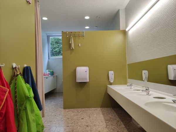 Sanitäreinrichtung des Kindergartens, rechts sind kindergerechte Waschbecken zu sehen