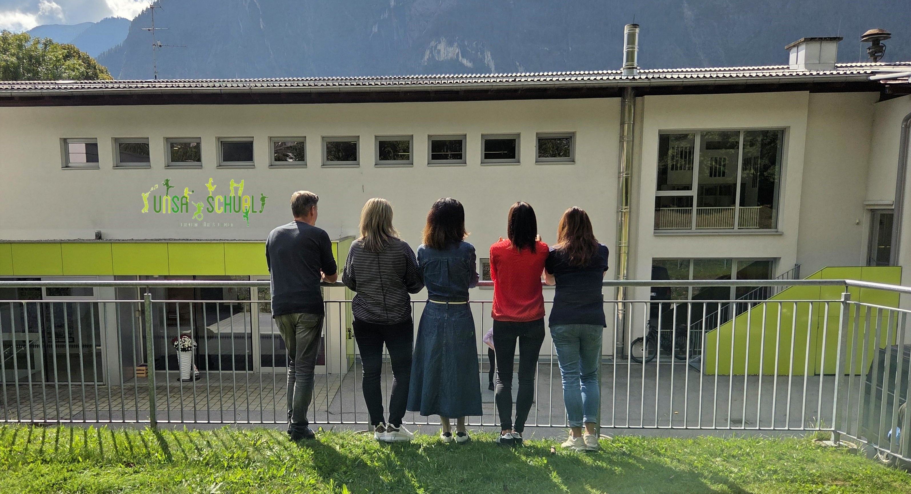 Im Vordergrund ist das Lehrpersonal, im Hintergrund die Volksschule